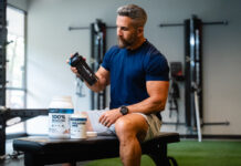 Koncentratizolat czy hydrolizat – którą proteinę serwatkową wybrać dla swoich celów treningowych Kilka dużych słoików protein serwatkowych w rzędzie na białym tle z miarkami proszku