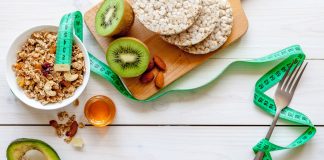 Dieta redukcyjna w sporcie – jak wygląda i kiedy się ją stosuje? Dieta redukcyjna - ułożone na stole zdrowe produkty żywnościowe i centymetr.