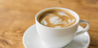 Korzyści zdrowotne kawy. Jak arabika może wpłynąć na Twoje zdrowie? Filiżanka pełna kawy z mleczną pianka