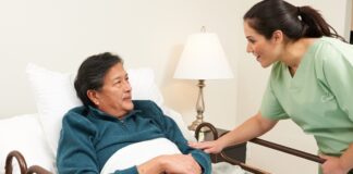 Medycyna paliatywna – czym jest i kto może z niej skorzystać? Lekarz w białym kitlu trzyma dłoń starszego pacjenta na szpitalnym łóżku z rodziną