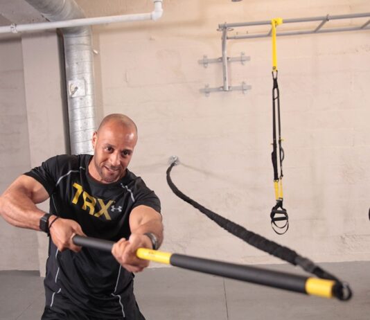 TRX suspension – jak ekspander zawieszeniowy buduje siłę, wydolność i stabilizację w każdych warunkach? Mężczyzna i kobieta trenują z taśmami TRX na siłowni i w domu pokazując wszechstronność