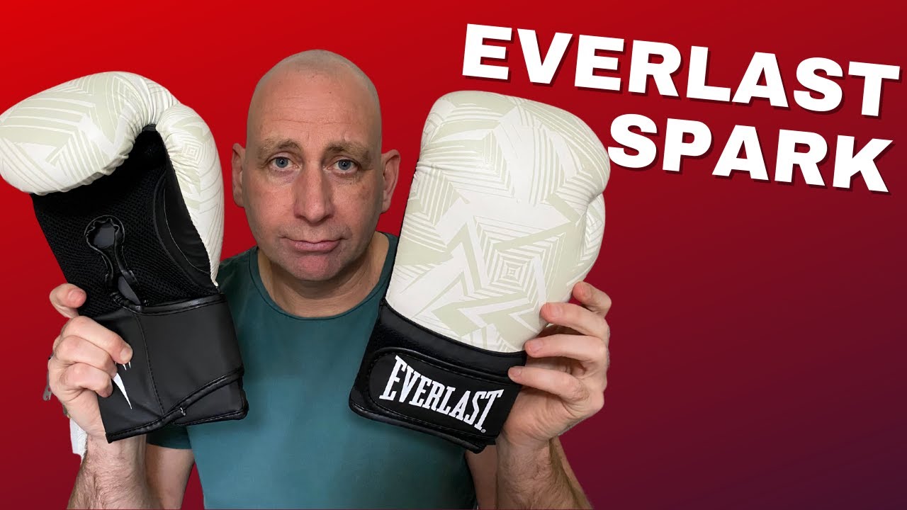 Bokser zakładający czerwone rękawice RDX na treningu w sali bokserskiej