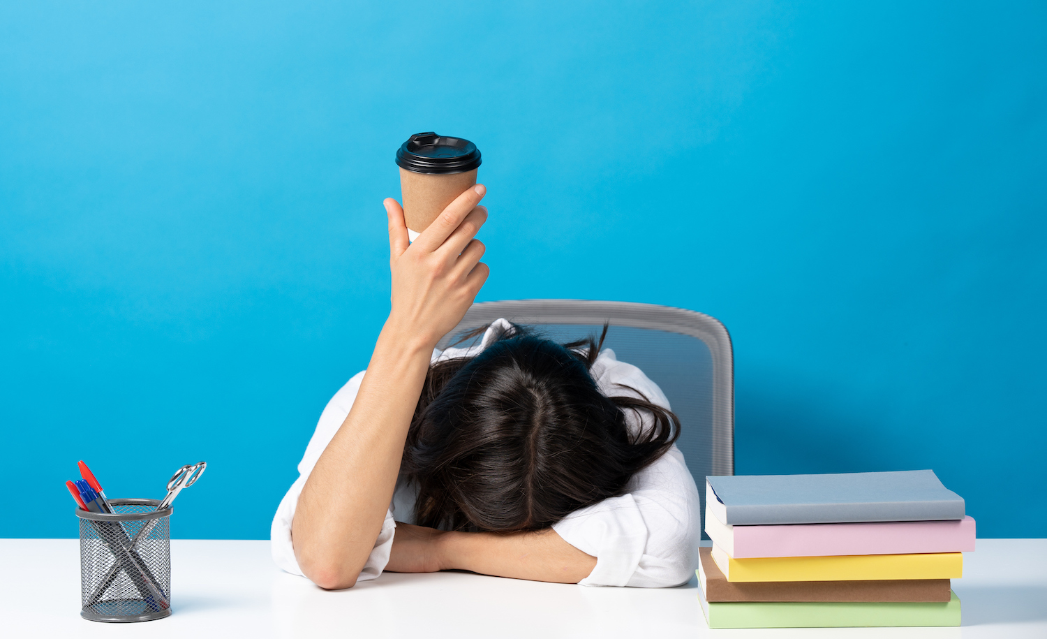 kobieta leżąca w łóżku z pustym kubkiem kawy obok nie mogąc zasnąć