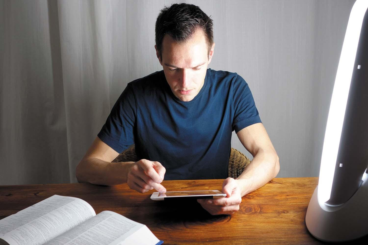 bliska widok białej lampy do fototerapii z ekranem i przyciskami na drewnianym stoliku