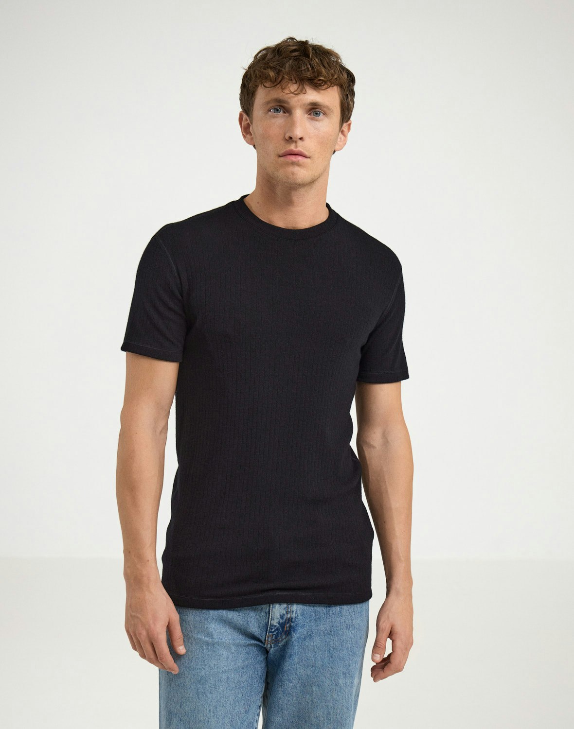 mężczyzna w czarnym merino pod kurtką narciarską zjeżdżający na nartach w śniegu