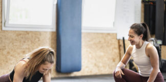 Trening HIIT: krótkie sesje, które spalają tłuszcz jeszcze parę godzin po ćwiczeniach Kobieta w sportowym stroju wykonuje burpees w jasnej sali fitness podczas dynamicznego treningu HIIT