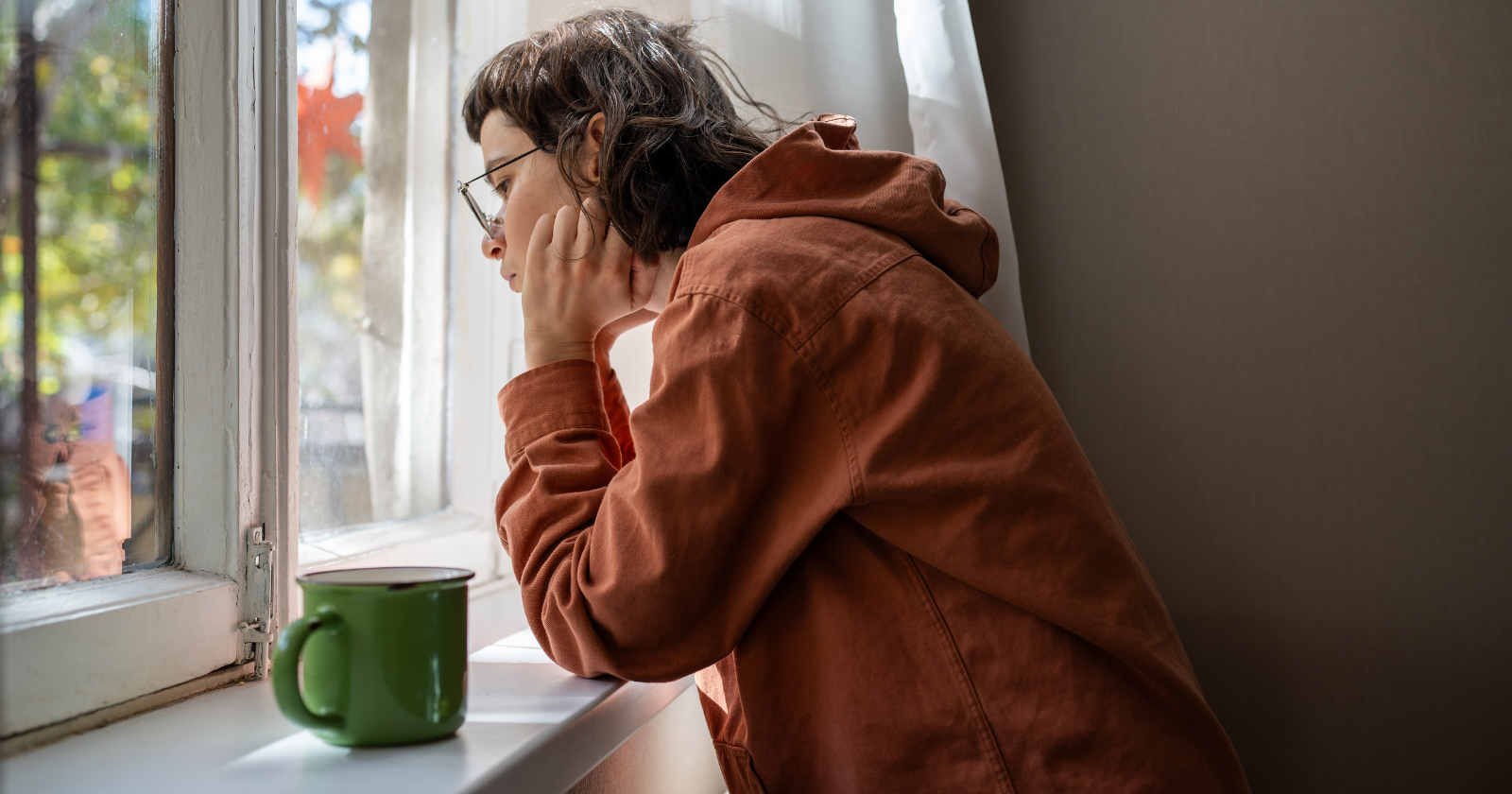 mężczyzna w biurze z kubkiem kawy masujący skronie z bólu głowy