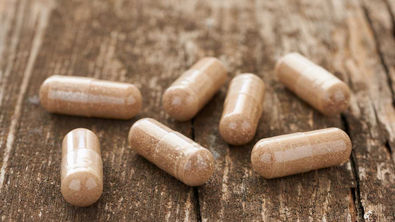 kobieta w wieku 30 lat połykająca kapsułkę ketonów z wodą