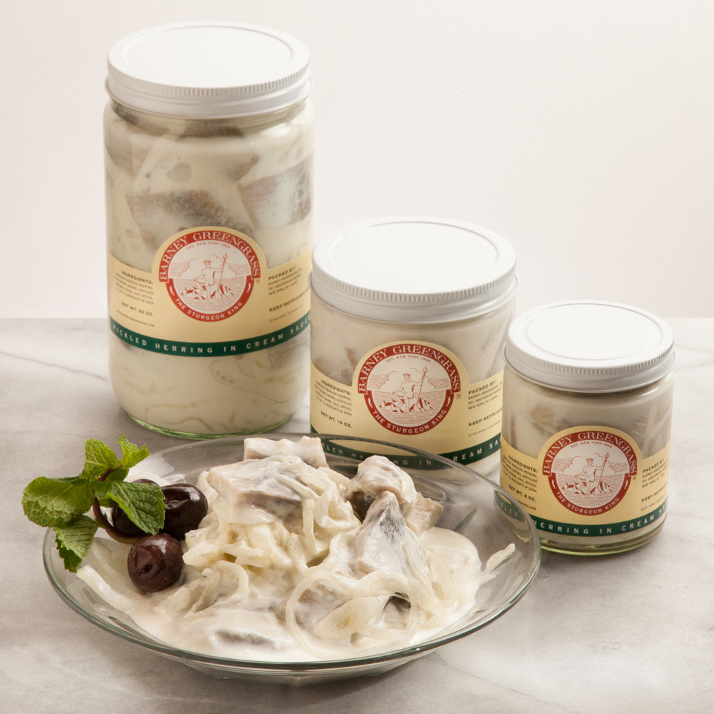 kilka słoików śledzi w occie stojących na półce sklepowej z etykietami