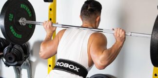 Pas kulturystyczny skórzany – jak wybrać model, który wesprze Twoje plecy w czasie ciężkich serii? Skórzany pas kulturystyczny na modelu podczas przysiadu ze sztangą na siłowni