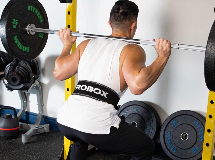 Skórzany pas kulturystyczny na modelu podczas przysiadu ze sztangą na siłowni