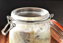 Śledzie w occie – czy ta powszechna przekąska naprawdę zasługuje na miano zdrowej żywności? talerz z marynowanymi śledziami w occie, cebulą i ziołami na drewnianym stole