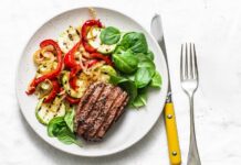 Dieta paleo dla sportowców – czy jedzenie jak przodkowie faktycznie poprawia wydolność i przyspiesza regenerację? Atletyczny mężczyzna je paleo posiłek z mięsem warzywami owocami i orzechami po treningu