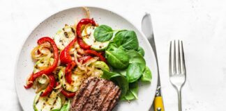 Dieta paleo dla sportowców – czy jedzenie jak przodkowie faktycznie poprawia wydolność i przyspiesza regenerację? Atletyczny mężczyzna je paleo posiłek z mięsem warzywami owocami i orzechami po treningu