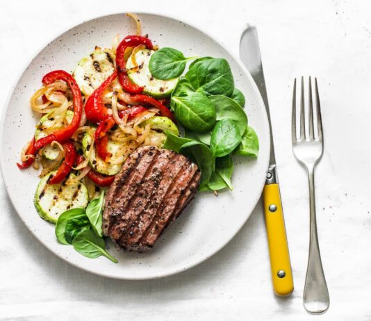 Dieta paleo dla sportowców – czy jedzenie jak przodkowie faktycznie poprawia wydolność i przyspiesza regenerację? Atletyczny mężczyzna je paleo posiłek z mięsem warzywami owocami i orzechami po treningu