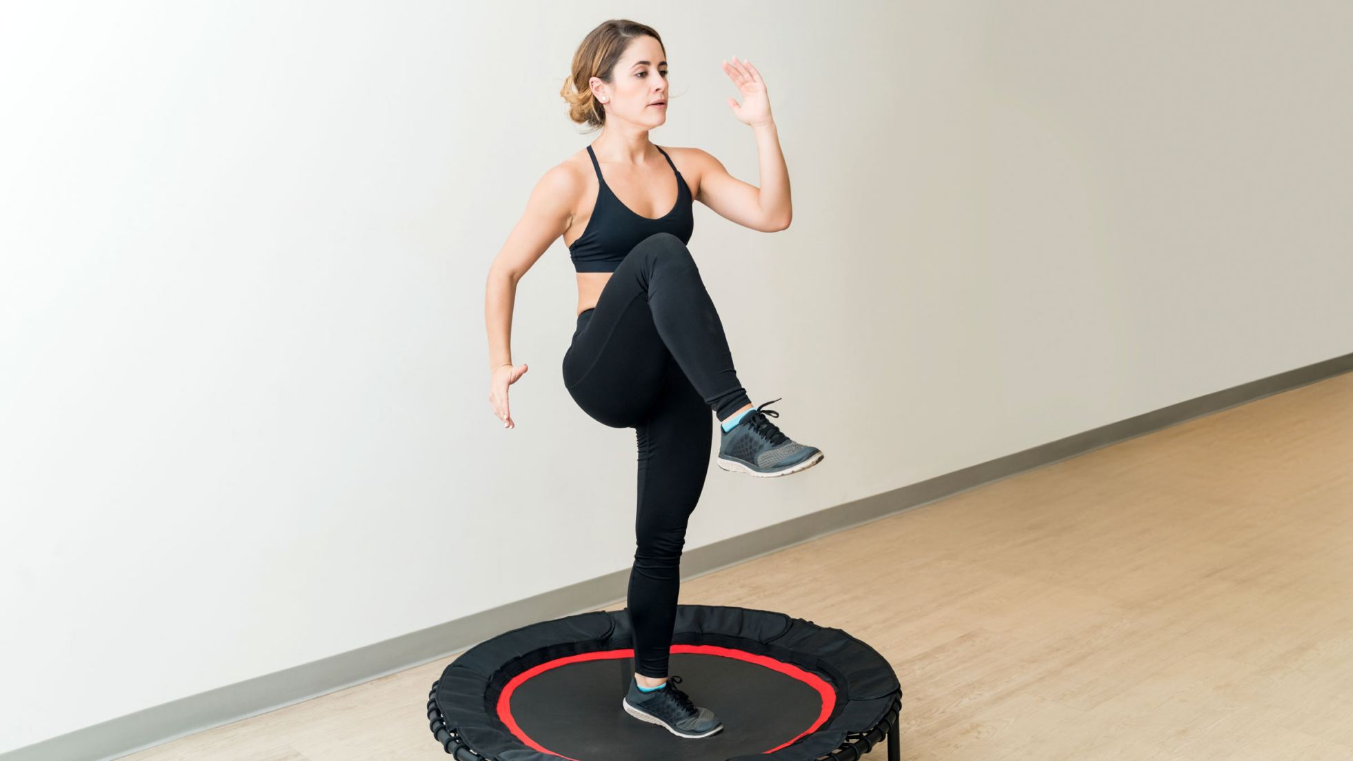 Bezpieczne odbicie w czasie zajęć Ćwicząca osoba miękko ląduje na trampolinie fitness w klubowej sali