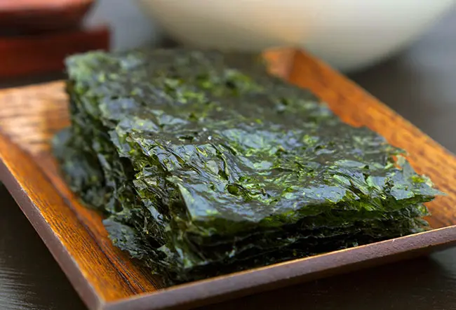 Nori w kuchni japońskiej Domowe rolki sushi owinięte ciemnym arkuszem nori na desce